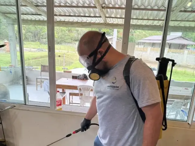 Técnico da Ambiente com EPI aplicando dedetização em cozinha