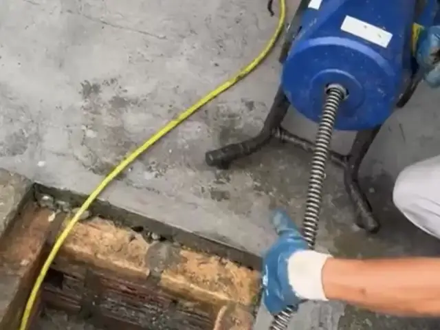 Técnico da Ambiente desentupindo caixa de inspeção com máquina rotativa
